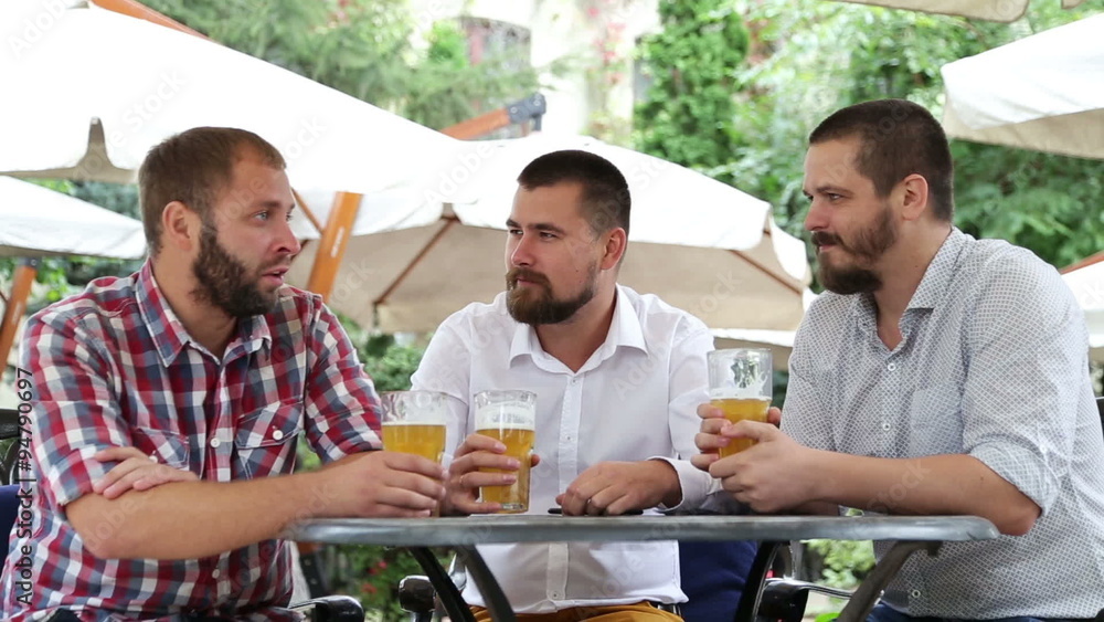 Three men with beards sitting in cafe, drinking beer and talking Three men with beards sitting in cafe, drinking beer and talking