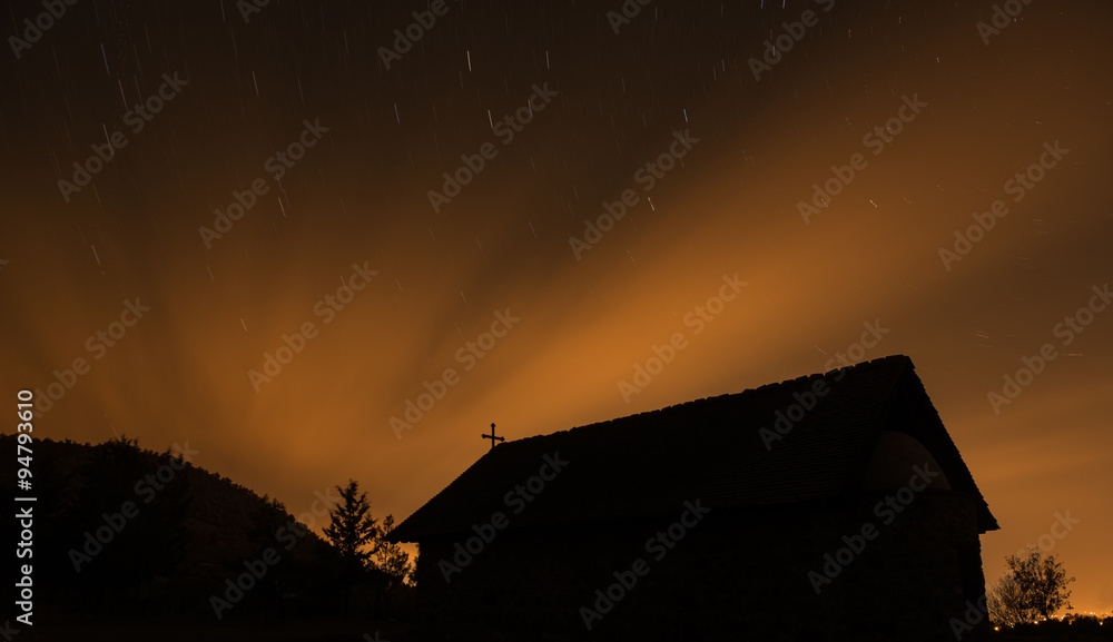 Christian Church in silhouette during a starry night and orange