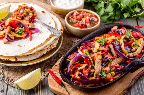 Pork fajitas with onions and colored pepper, served with tortill photo