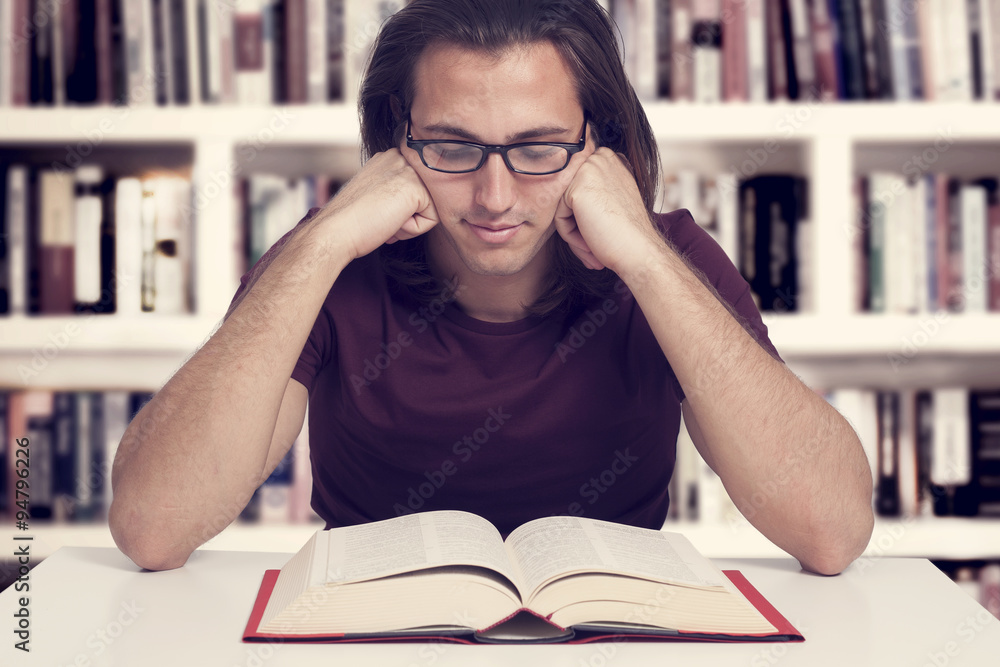 Young man reading book in library Young man reading book in library
