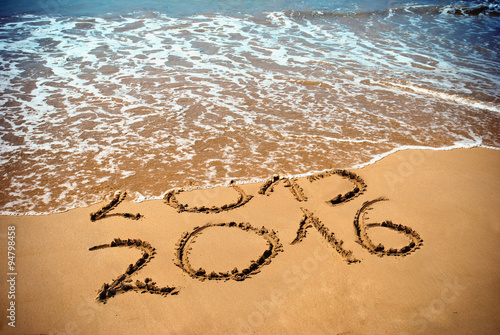 New Year 2016 is coming concept - inscription 2015 and 2016 on a beach sand  the wave is covering digits 2015