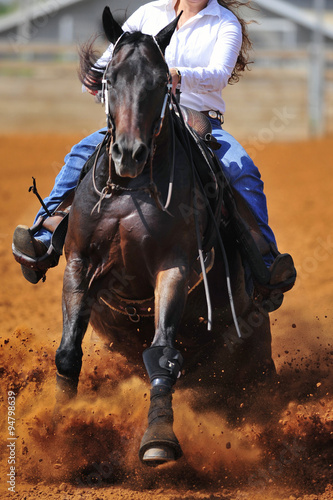 A close up view of a rider sliding the horse in the dirt