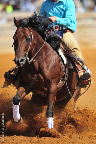 Fototapeta Naklejka Na Ścianę i Meble -  A close up view of a rider sliding the horse in the dirt