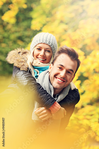 Young romantic couple piggybacking in the park in autumn