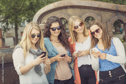 Foto Vier junge Frauen mit Smartphones