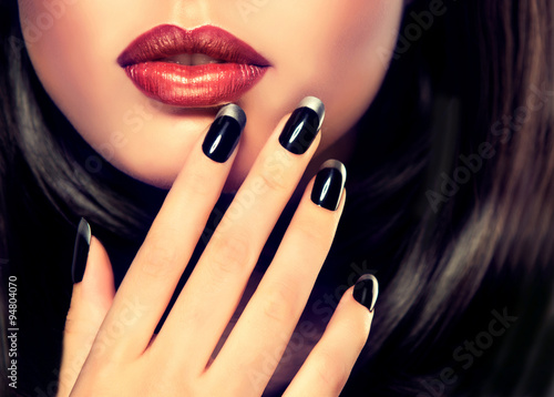 Beautiful model brunette shows black and silver French manicure on nails. Luxury fashion style, manicure nail , cosmetics and makeup .
