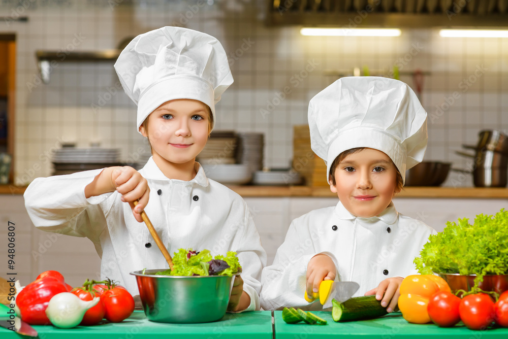 Funny happy chef boys cooking at restaurant kitchen. concept of vegetarianism Funny happy chef boys cooking at restaurant kitchen. concept of vegetarianism