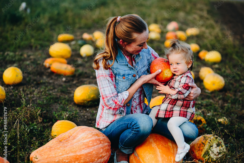 Fototapeta premium Mother and daughter sitting on pumpkins