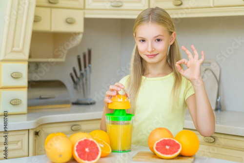 Child with oranges. Girl squeezed fresh orange juice and showing Ok
