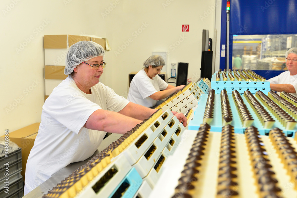 ältere Frauen arbeiten am Fliessband bei der Herstellung von Pralinen in einer Fabrik // older