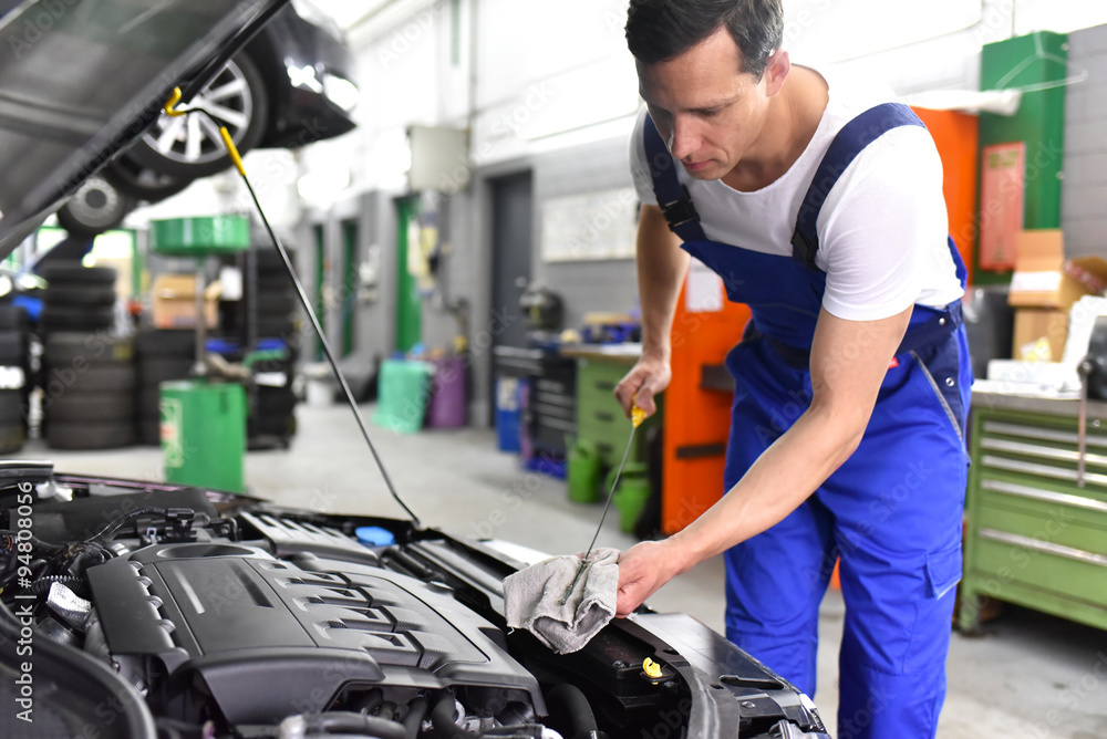 Mechaniker in einer Werkstatt kontrolliert den Füllstand vom Motoröl eines Autos // mechanic in a workshop controls the level of the oil of a car Mechaniker in einer Werkstatt kontrolliert den Füllstand vom Motoröl eines Autos // mechanic in a workshop controls the level of the oil of a car