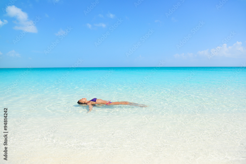 Woman swimming in ocean relaxing enjoying the sun bathing in peaceful blue water. Sexy female adult floating meditating in the sea.