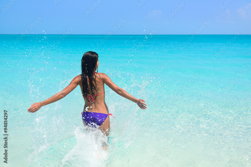Beach vacation in tropical travel destination. Sexy woman in bikini feeling free swimming splashing water in blue ocean enjoying her sunny holidays. Concept of people having fun under the sun. Beach vacation in tropical travel destination. Sexy woman in bikini feeling free swimming splashing water in blue ocean enjoying her sunny holidays. Concept of people having fun under the sun.