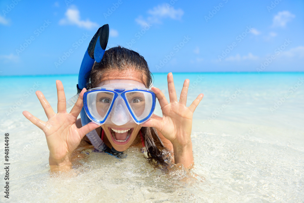 Naklejka premium Beach vacation fun woman wearing a snorkel scuba mask making a goofy face while swimming in ocean water. Closeup portrait of Asian girl on her travel holidays. Summer or winter destination.