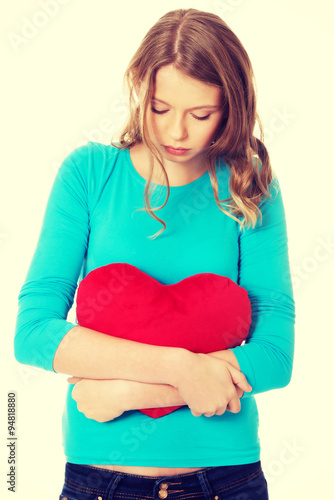Young woman with heart shaped pillow