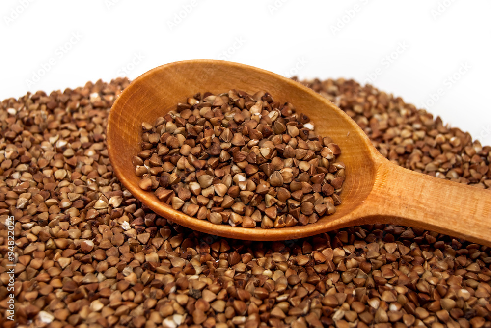Buckwheat with a wooden spoon on a white background Buckwheat with a wooden spoon on a white background