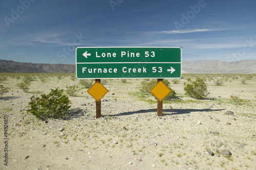 A sign in Death Valley National Park pointing to Furnace Creek and Lone Pine, CA photo