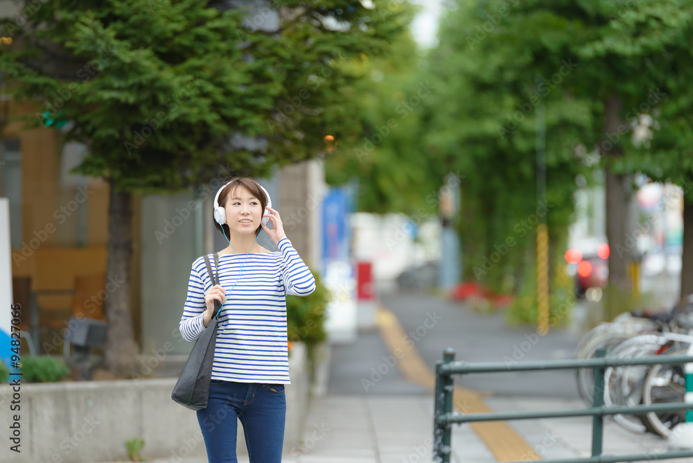 Fototapeta premium ヘッドホンで音楽を聞きながら歩く女性