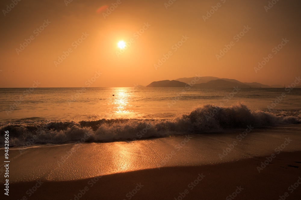 sunrise above sea against hills with running waves