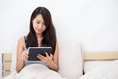 Asian woman using the digital tablet in bed