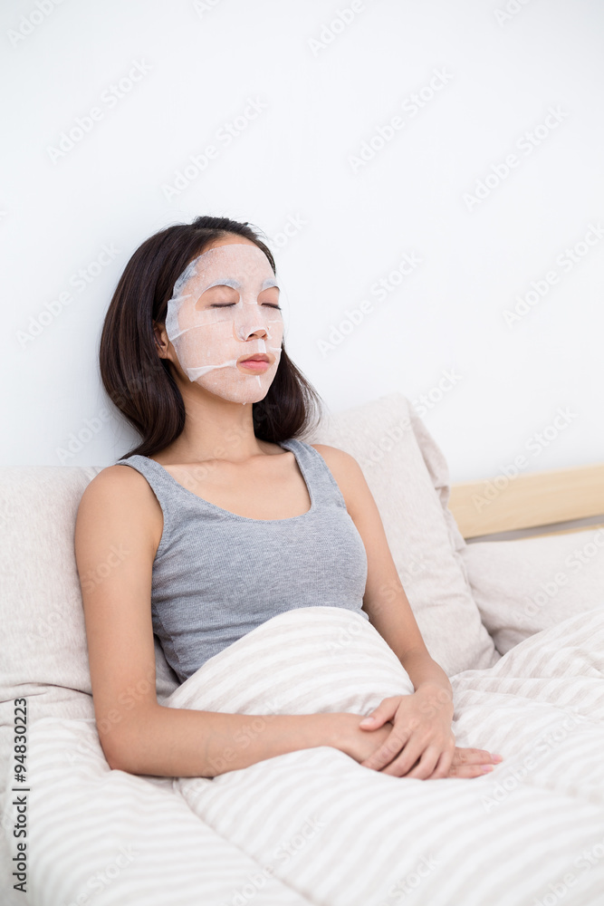Woman sitting in bed with her mask sheet Woman sitting in bed with her mask sheet