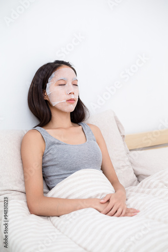Woman sitting in bed with her mask sheet