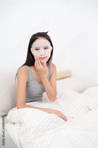 Woman using the facial mask in bed