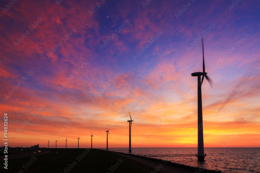 Obraz premium Beautiful sunset at the dike with wind turbines at the Markermeer in the Netherlands 