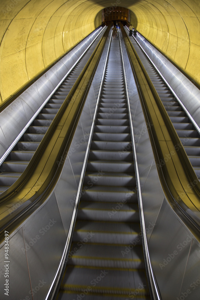 An empty escalator moves through oval tube of light to the Washington D.C. Metrorail commuter trains. An empty escalator moves through oval tube of light to the Washington D.C. Metrorail commuter trains.