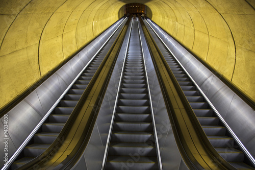 An empty escalator moves through oval tube of light to the Washington D.C. Metrorail commuter trains.