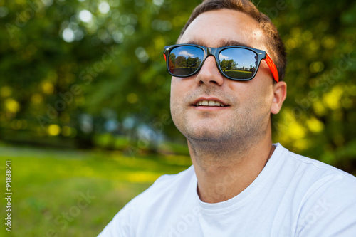 Young man in white shirt is sitting in the park.