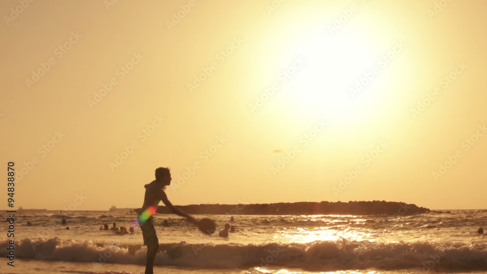 Boy playing beach tennis at sunset Boy playing beach tennis at sunset