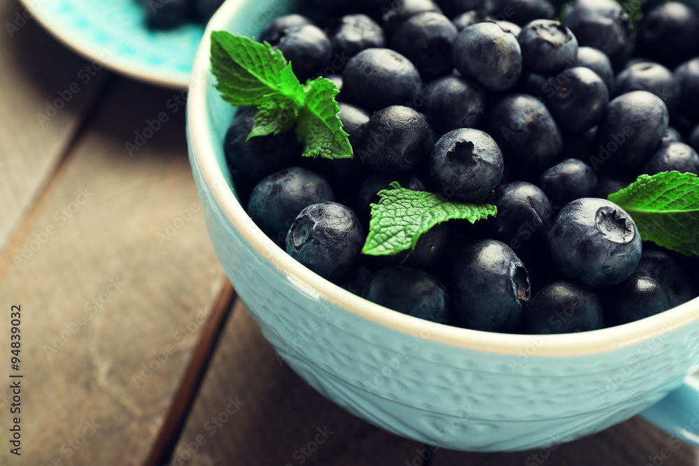 Fresh blueberries in cup on wooden table close up Fresh blueberries in cup on wooden table close up
