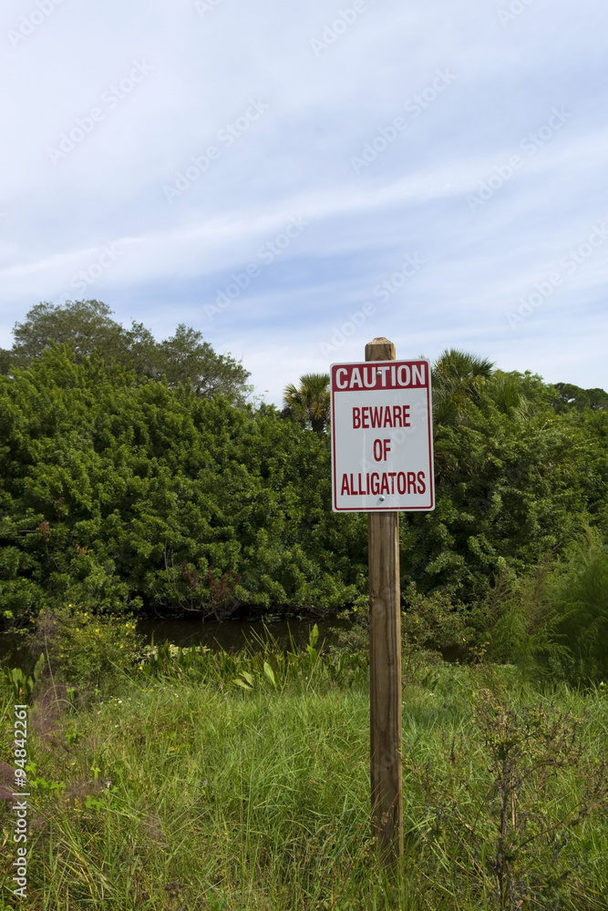 Caution beware of alligators sign close to a lake in Florida Caution beware of alligators sign close to a lake in Florida