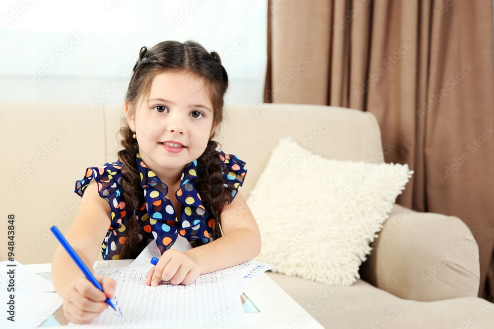 Cute little girl doing her homework, close-up, on home interior background Cute little girl doing her homework, close-up, on home interior background