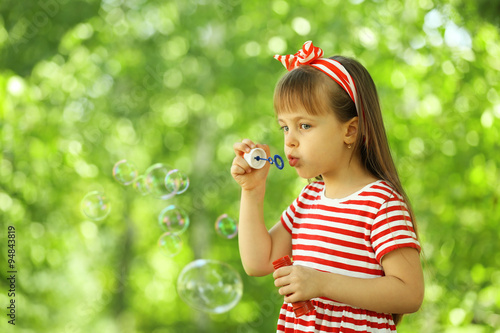 Little girl playing with bubbles in the park