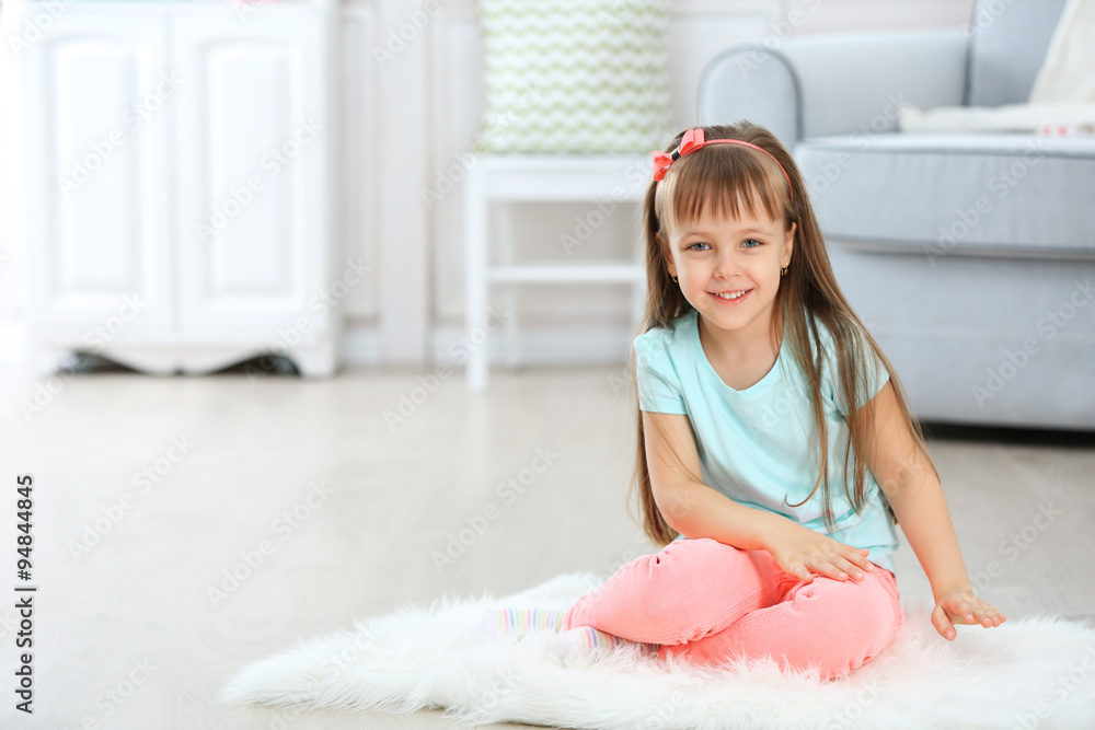 Little cute girl sitting on carpet, on home interior background Little cute girl sitting on carpet, on home interior background