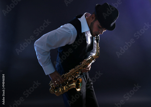 Elegant saxophonist plays jazz on dark background