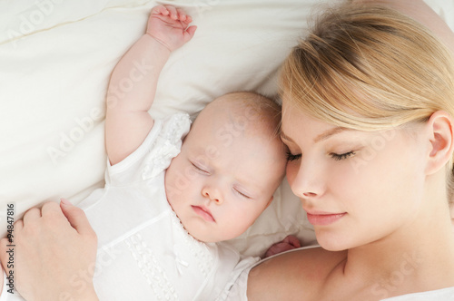 Young mother and her baby, sleeping in bed. Mother and baby. Hap