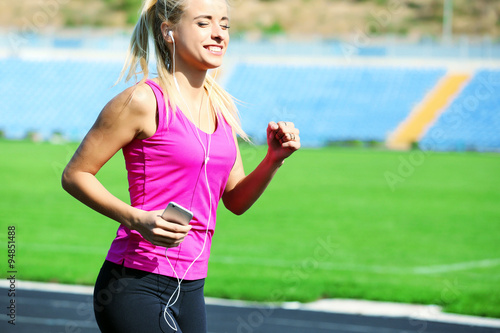 Young woman listening to music on the stadium