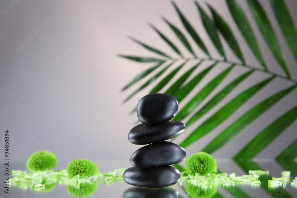 Spa stones and green palm branch on grey background Spa stones and green palm branch on grey background