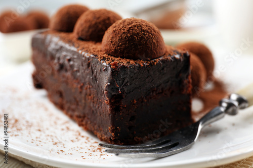 Slice of chocolate cake with a truffle on plate closeup