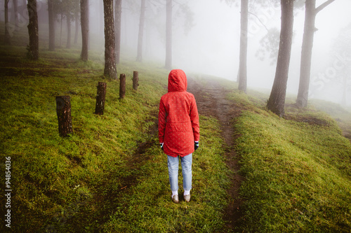 woman wear red coat  turn back on path way with fog