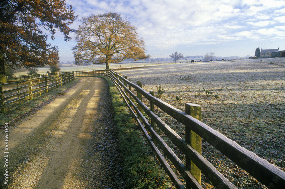 Morning view of a country road and wood fence in Upper Brails, England