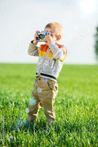 Little boy with an old camera shooting outdoor.