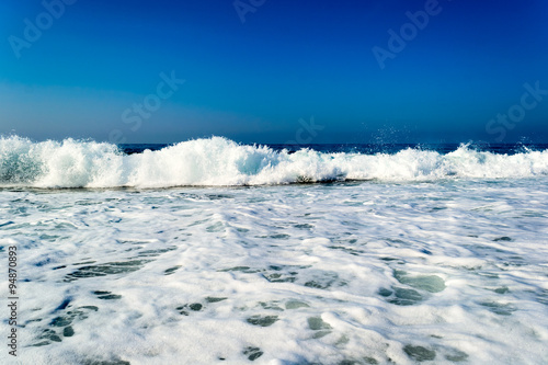 Waves breaking on a stony beach, forming sprays