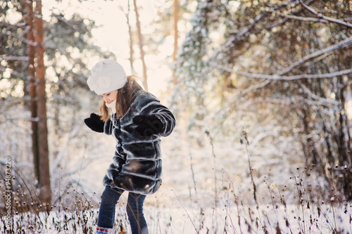 child girl playing outdoor in snowy winter forest