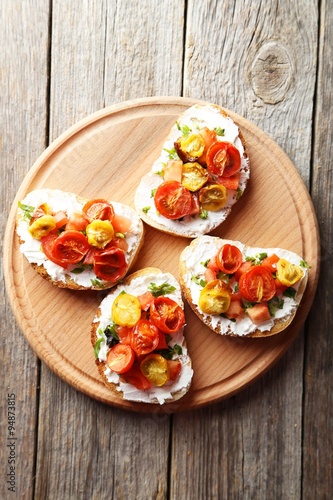 Tasty fresh bruschetta with tomatoes on cutting board on grey wo