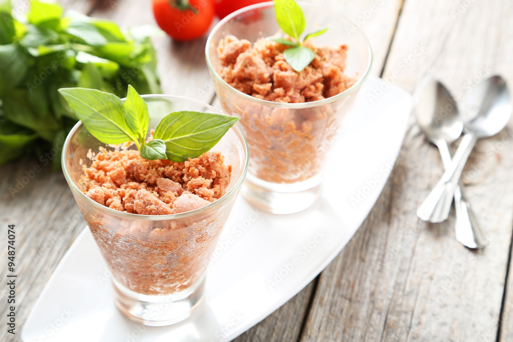 Glass with granita from fresh tomatoes on grey wooden background Glass with granita from fresh tomatoes on grey wooden background
