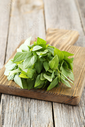 Basil leaves on cutting board grey wooden background